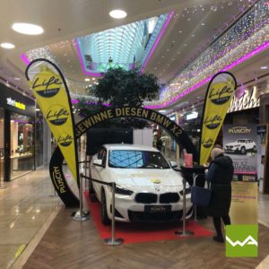 Beachflags neben einem neuen BMW X2 im Einkaufszentrum Plus City